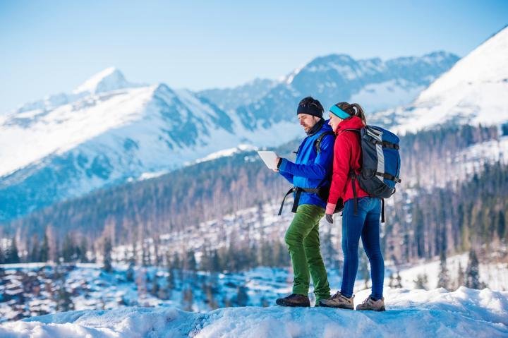 young couple hiking outside in sunny winter mountains